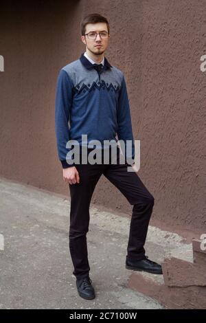 Porträt des stilvollen Brunet jungen Mann, trägt blauen Pullover, auf einer Straße der Stadt stehen Stockfoto