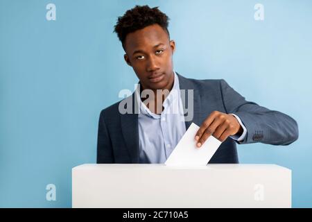 Konzentrierter afroamerikanischer Geschäftsmann, der bei der Abstimmung Papier zieht Stockfoto
