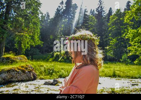 Junge blonde Kind mit einer Krone auf dem Kopf in einem Wald wie eine Fee aussehen Stockfoto