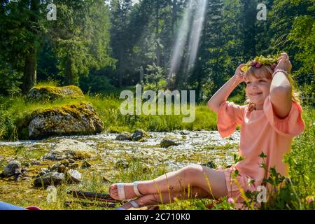 Junge blonde Kind mit einer Krone auf dem Kopf in einem Wald wie eine Fee aussehen Stockfoto