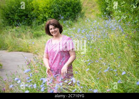 Frau mittleren Alters auf einer schönen wilden Wiese im Sommer Stockfoto