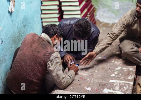 Neu Delhi / Indien - 18. Februar 2020: Gruppe von indischen Mann mit Smartphone in leeren Laden in Alt-Delhi spielen Stockfoto