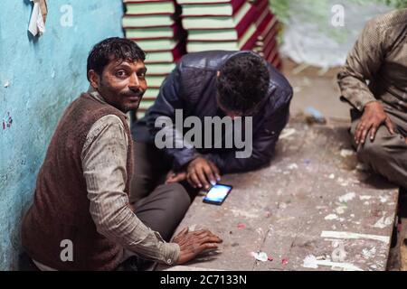 Neu Delhi / Indien - 18. Februar 2020: Gruppe von indischen Mann mit Smartphone in leeren Laden in Alt-Delhi spielen Stockfoto