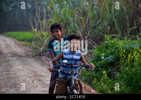 Zwei indische Teenager-Jungen auf dem Fahrrad in einer Dorfstraße, selektive Fokussierung Stockfoto
