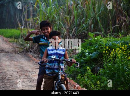 Zwei indische Teenager-Jungen auf dem Fahrrad in einer Dorfstraße, selektive Fokussierung Stockfoto