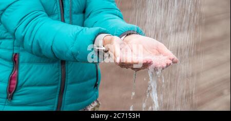 Durstige Frau, die Wasser aus der Dusche mit ihren Händen im Freien auf dem Land fängt. Stockfoto