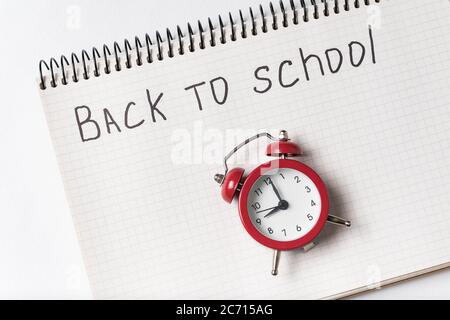 Notizblock mit den Worten ZURÜCK ZUR SCHULE und Vintage-Wecker aus nächster Nähe Stockfoto