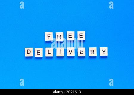 Kostenloser Versand Schriftzug in Holzbuchstaben auf blauem Hintergrund, Draufsicht. Servicekonzept, Lieferung, kontaktlose Lieferung, Promotion, kostenlos. Stockfoto
