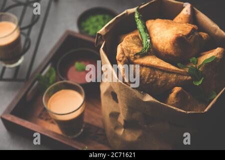 Samosa - Gebratenes Gebäck in Dreieckform mit herzhafter Füllung, beliebte indische Teezeit-Snacks, serviert mit grünem Chutney und Tomatenketchup Stockfoto