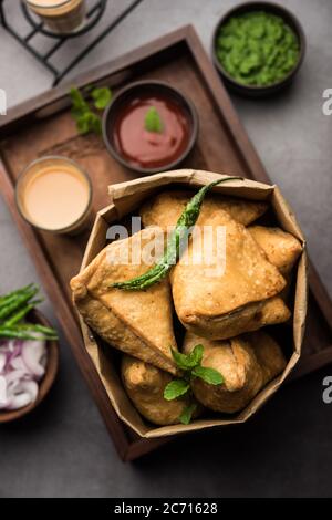 Samosa - Gebratenes Gebäck in Dreieckform mit herzhafter Füllung, beliebte indische Teezeit-Snacks, serviert mit grünem Chutney und Tomatenketchup Stockfoto