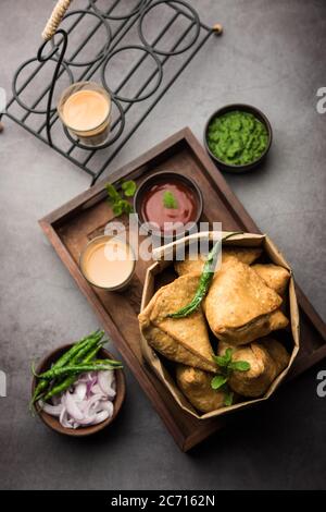 Samosa - Gebratenes Gebäck in Dreieckform mit herzhafter Füllung, beliebte indische Teezeit-Snacks, serviert mit grünem Chutney und Tomatenketchup Stockfoto