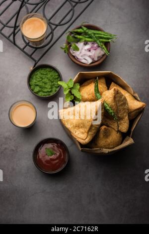 Samosa - Gebratenes Gebäck in Dreieckform mit herzhafter Füllung, beliebte indische Teezeit-Snacks, serviert mit grünem Chutney und Tomatenketchup Stockfoto