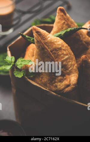 Samosa - Gebratenes Gebäck in Dreieckform mit herzhafter Füllung, beliebte indische Teezeit-Snacks, serviert mit grünem Chutney und Tomatenketchup Stockfoto