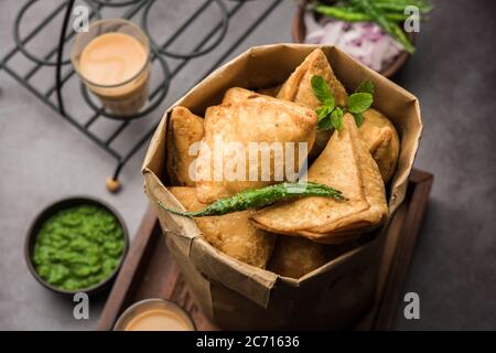 Samosa - Gebratenes Gebäck in Dreieckform mit herzhafter Füllung, beliebte indische Teezeit-Snacks, serviert mit grünem Chutney und Tomatenketchup Stockfoto