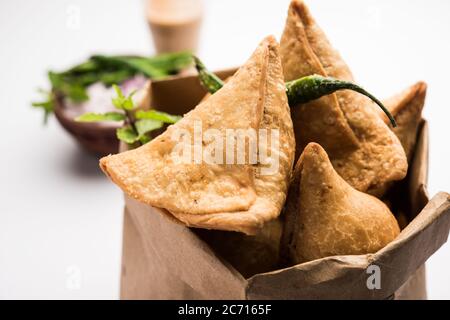 Samosa - Gebratenes Gebäck in Dreieckform mit herzhafter Füllung, beliebte indische Teezeit-Snacks, serviert mit grünem Chutney und Tomatenketchup Stockfoto