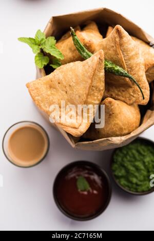 Samosa - Gebratenes Gebäck in Dreieckform mit herzhafter Füllung, beliebte indische Teezeit-Snacks, serviert mit grünem Chutney und Tomatenketchup Stockfoto