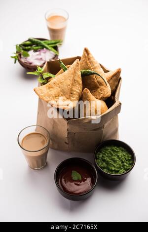 Samosa - Gebratenes Gebäck in Dreieckform mit herzhafter Füllung, beliebte indische Teezeit-Snacks, serviert mit grünem Chutney und Tomatenketchup Stockfoto