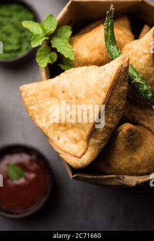Samosa - Gebratenes Gebäck in Dreieckform mit herzhafter Füllung, beliebte indische Teezeit-Snacks, serviert mit grünem Chutney und Tomatenketchup Stockfoto