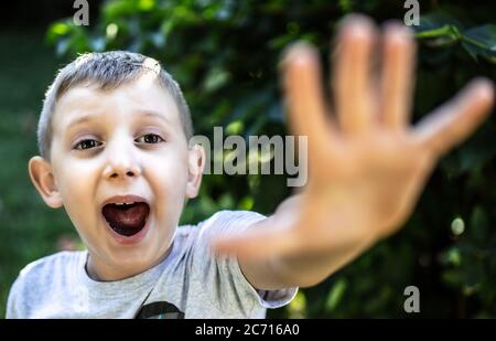 Erschreckenes Kind schreiend und mit offener Hand zur Kamera. Stockfoto