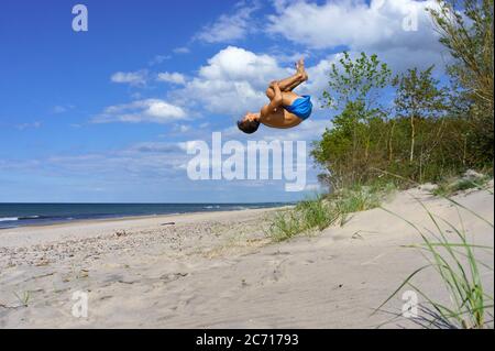 Ein junger Mann ruht auf dem Meer, ein Athlet meditiert an der Küste, Ostsee, Kaliningrad, Russland, 6. Juni 2020 Stockfoto