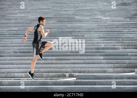 Sportler läuft und springt am Morgen. Mann in Sportbekleidung Joggen auf Treppen Stockfoto