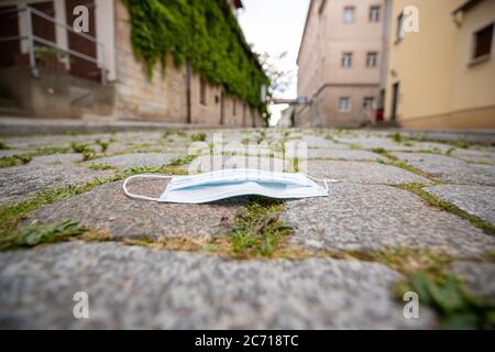 Pirna, Deutschland. Juli 2020. Auf dem Bürgersteig der historischen Altstadt der sächsischen Stadt Pirna wird eine Kopfsteinpflastermaske über Mund und Nase platziert. Für manche Menschen ist das Tragen der Maske einfach ärgerlich und doch gibt es einen Teil der Gesellschaft, der sie zum Selbstschutz gegen Infektionen trägt. Quelle: Daniel Schäfer/dpa-Zentralbild/ZB/dpa/Alamy Live News Stockfoto