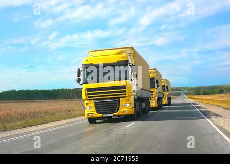 Gelbe LKWs auf Landstraße begleiten Stockfoto