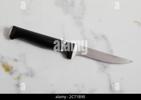 Ein professionelles isoliertes Küchenmesser auf weißem Marmorhintergrund. Küchengeschirr aus Stahl Stockfoto