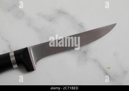 Ein professionelles isoliertes Küchenmesser auf weißem Marmorhintergrund. Küchengeschirr aus Stahl Stockfoto