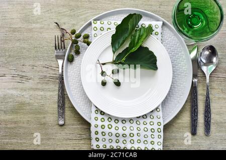 Sommertisch in Grüntönen. Teller, Besteck, Serviette und Erle Zweig. Stockfoto