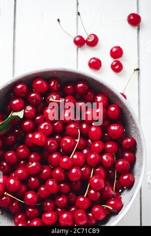 Frische Kirschen im Sieb auf weißem Holzhintergrund. Stockfoto