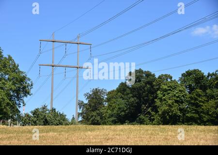 Blick auf den Stromübertragungsturm von Hochspannungsstrom in der Mitte der Wiese in der Schweiz Landschaft während sonnigen Sommer schönen Tag. Stockfoto