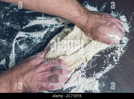 Nahaufnahme des Menschen Kneten Teig ein Holztisch, Lebensmittelzubereitung Konzept Stockfoto