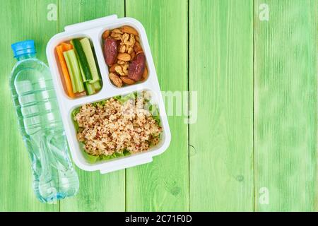 Vegane Lunchbox, Wasser in der Flasche, grüner Hintergrund, Kopierraum. Stockfoto