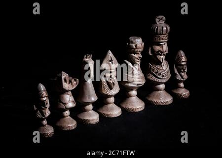 Schachfiguren in einer Reihe auf schwarzem Hintergrund Stockfoto