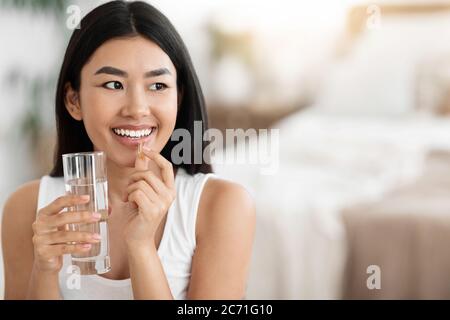 Glücklich Asiatische Frau Einnahme Pille Und Halten Glas Wasser Stockfoto