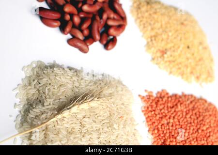 Haufen ungekochten rohen Reiskörns, roten Linsen, Taubenerde und rote Niere. Reiskörner, Mungbohnen, rote Linsen und rote Niere isoliert auf weiß. Stockfoto