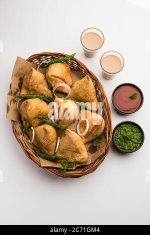 Samosa - Gebratenes Gebäck in Dreieckform mit herzhafter Füllung, beliebte indische Teezeit-Snacks, serviert mit grünem Chutney und Tomatenketchup Stockfoto