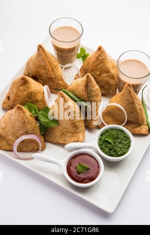 Samosa - Gebratenes Gebäck in Dreieckform mit herzhafter Füllung, beliebte indische Teezeit-Snacks, serviert mit grünem Chutney und Tomatenketchup Stockfoto