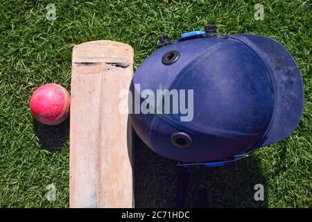 Rosa Cricket Ball und Fledermaus mit Halmet auf grünem Gras. Stockfoto