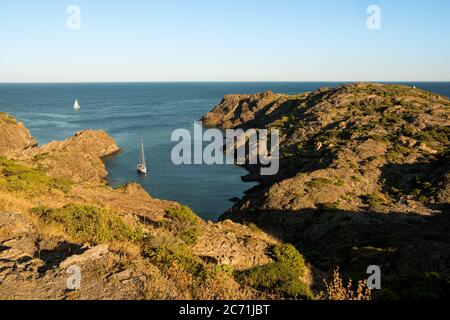 Blick auf die kleine cala, eine kleine Bucht und felsigen Strand an der costa brava Küste in spanien mit einem kleinen Segelboot in Cap de creus, ein beliebtes Reiseziel Stockfoto