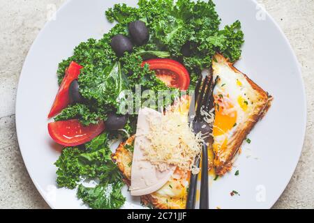 Gebackenes Ei mit Käse in Brot mit Salat auf einem weißen Teller. Stockfoto