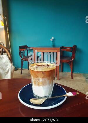 Eine Tasse Eiced Flat White in einem Hintergrund von blau-grünen Tapeten. Wunderschön gestaltetes Café in Südkorea. Perfekte erholsame Zeit im Urlaub Morgen. Stockfoto