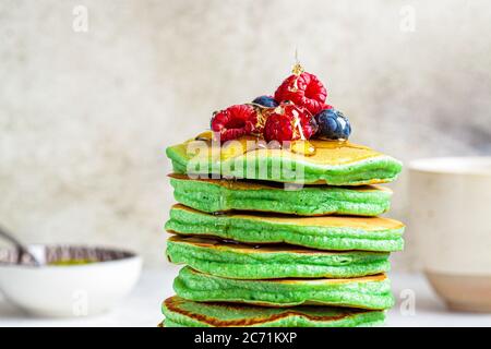 Matcha Tee Pfannkuchen mit Beeren, weißer Hintergrund. Gesundes veganes Lebensmittelkonzept. Stockfoto