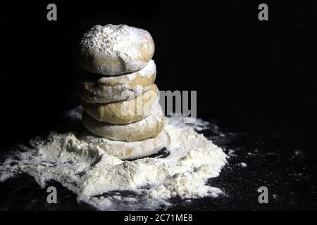 Stück Hefeteig mit Weizenmehl auf schwarzem Hintergrund. Brotball für Roti oder Chapati (indisches Fladenbrot). Stockfoto