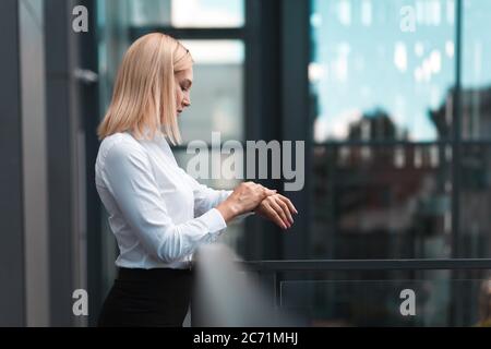 Schöne Geschäftsfrau mit weißen Haaren überprüft Zeit auf der Uhr Stockfoto