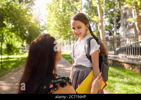 Zurück zur Schule. Kleines Mädchen mit Rucksack und ihre Mutter auf dem Weg zur Schule an sonnigen Tag. Stockfoto