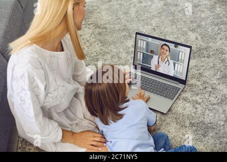 Mutter mit Sohn im Gespräch mit Arzt online von zu Hause. Eltern und kleiner Junge mit Videoanruf mit Kinderarzt auf Laptop Stockfoto