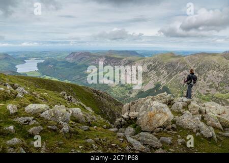 Eine einreisende Wanderin, die von der Spitze des Pillar, einem Berg im Lake District National Park in England, auf das Ennerdale Water blickt. Stockfoto