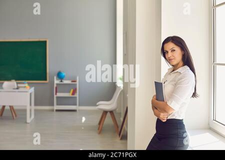 Lehrer mit einem Buch in der Hand, das in der Klasse steht. Stockfoto